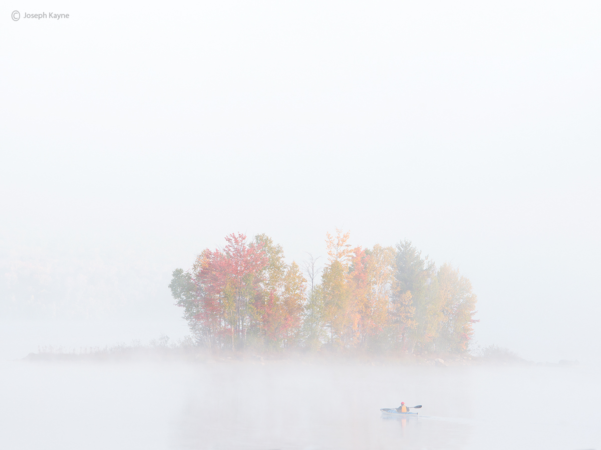 A Kayaker Cuts Through The Fog In a Vermont Pond